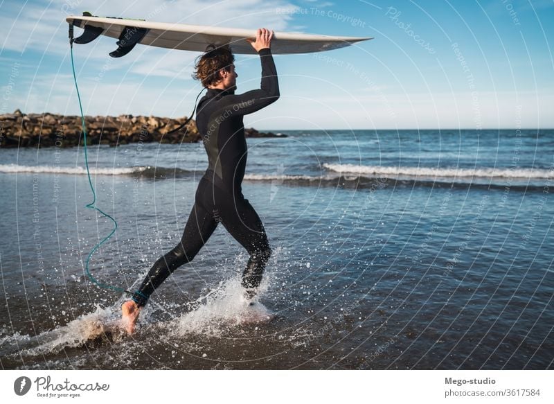 Surfer entering into the water with his surfboard. man sport surfing sea surfer ocean outdoors athletic scenic coastline waves background adventure sports