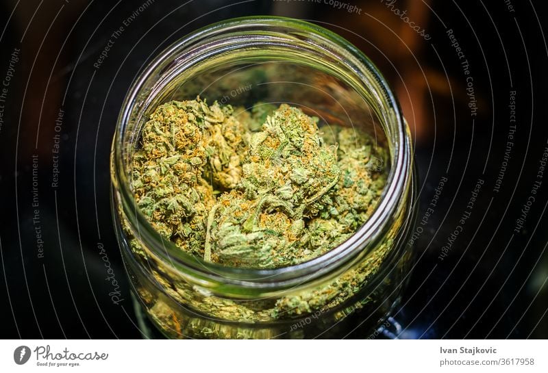 Cannabis flower buds in glass jar against dark background pot joint crime grinder cannabis addiction ganja smoking drug herb wild plant problem leaf herbal