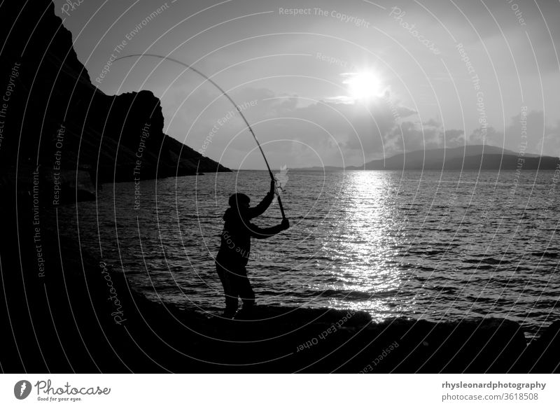 Young man fishing with feathers for mackerel B+W isle of mull scotland black white black and white fishing feathers fishing rod line hunting sport silhouette