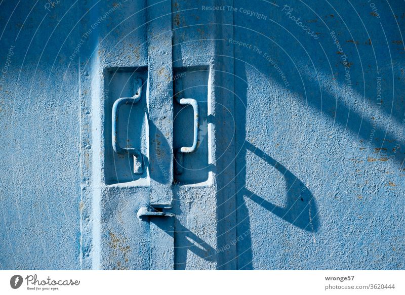 Close-up of two handles on a blue steel gate Shadow play shadow cast long shadows Goal Blue Garag Garage door Exterior shot Colour photo Deserted Day Closed