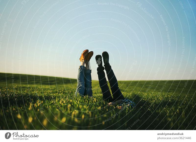 View of a man's and woman's legs sticking up out of tall green grass on summer day.selective focus. nois. people boyfriend girlfriend couple barefoot caucasian