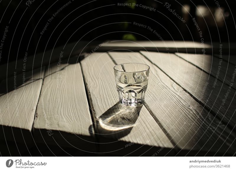 a glass of water on a white table with rays of the sun with nature background clear light wood fresh clean freshness drink pure transparent summer wooden shadow