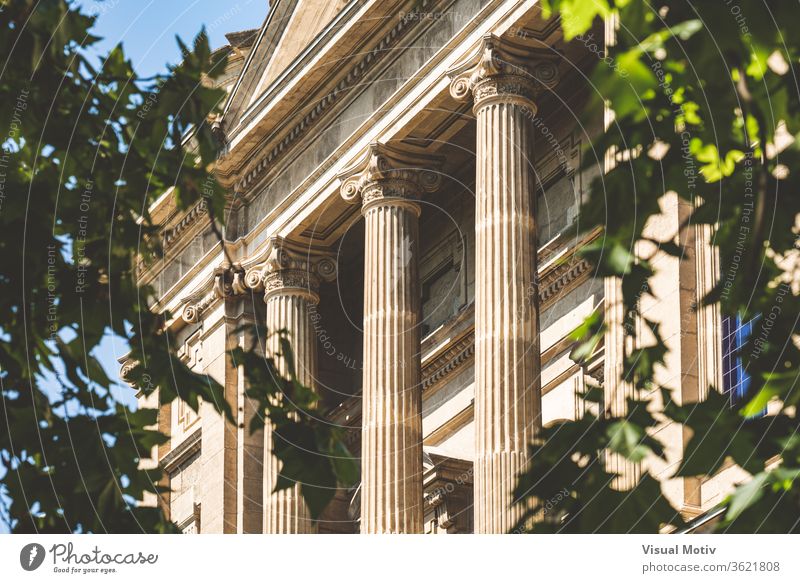 Ionic columns facade of the National Art Museum of Catalonia in Barcelona aka MNAC, surrounded by tree leaves building ornament historic old statue sunny