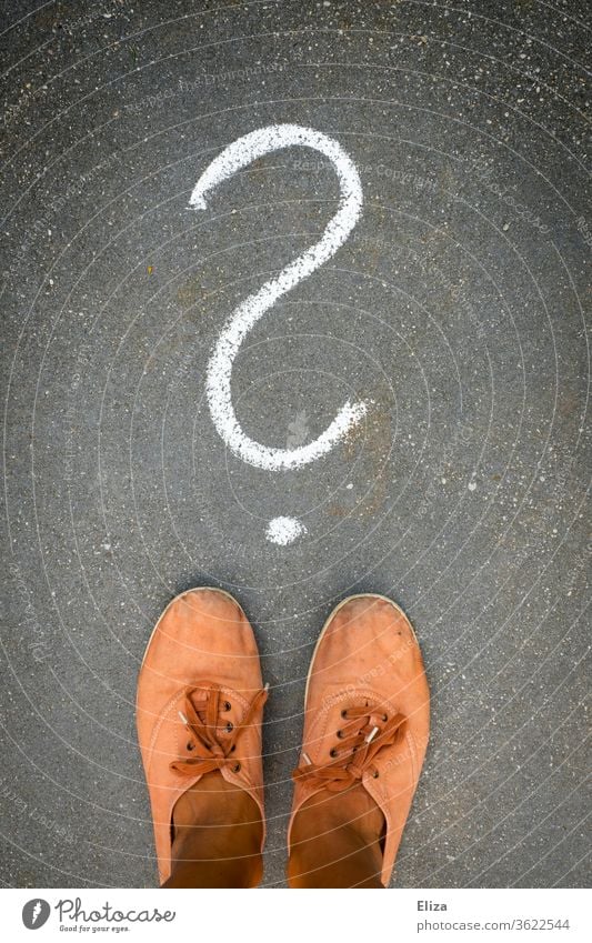 Feet stand in front of a question mark painted on the floor with chalk. Question, perplexity, indecision. Decide Perplexed Question mark disorientation