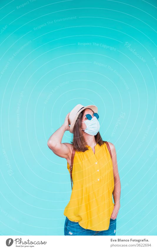 portrait of young woman outdoors over turquoise background wearing protective mask. Summer time and corona virus concept epidemic attitude saying infectious