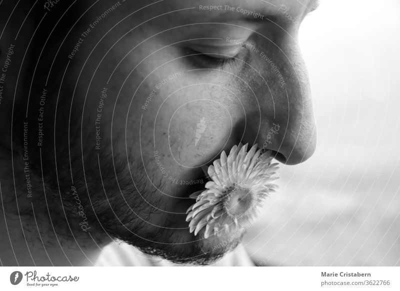 portrait of man with flower in mouth to show concept of kindness, power of words and vulnerability humanity black and white portrait kindness concept kind words