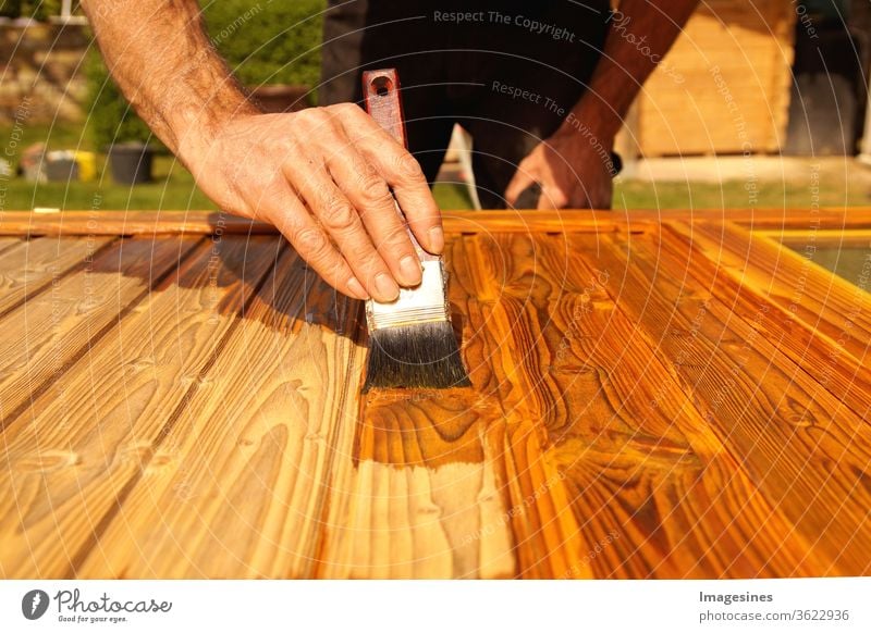 Glaze. Woodwork, painting wood. Hand of the craftsman painting a wooden door. Concept of renovation work, carpentry and woodwork. painter, painting wooden surface, wood preservation