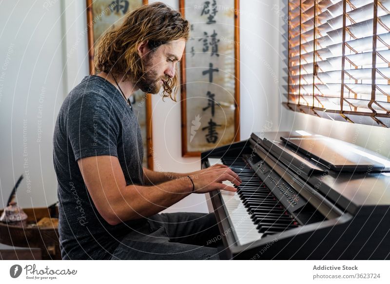 Talented man playing piano at home synthesizer musician instrument electronic talent male skill apartment cozy sit melody sound style entertain modern song guy