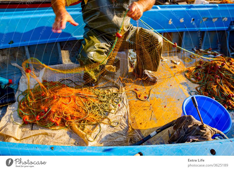 Fisherman is empty fish from net in his small boat - a Royalty Free Stock  Photo from Photocase