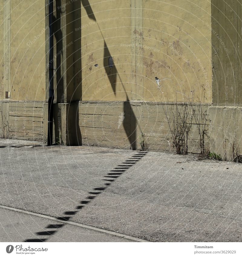 Old industrial building with street and cheerful pennant shadow Industrial building Wall (building) Shadow pennant chain Asphalt Street Flag lines Concrete