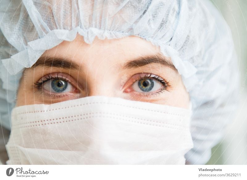 Close-up portrait of young female surgeon doctor or intern wearing protective mask and hat medical surgery concept emergency hospital work nurse care health