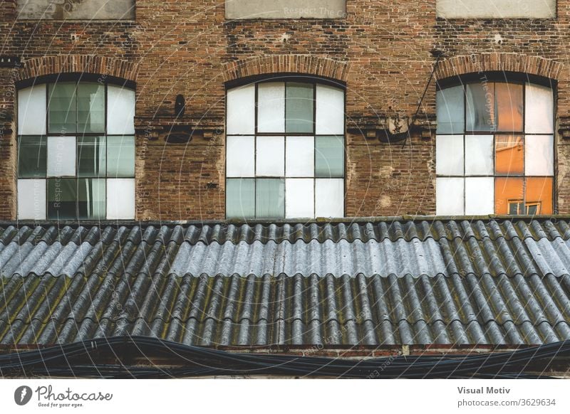 Windows and worn-out roof of an old abandoned textile factory at the afternoon light window building rooftop facade industry architecture architectural