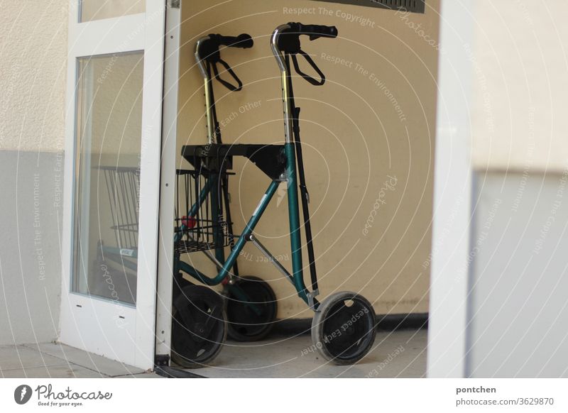 A rollator is placed in the entrance of an apartment building. Walker, aging. Rollator Walking aid age Entrance door Open Apartment house Senior citizen Healthy