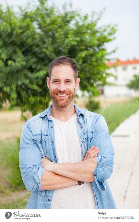 Casual guy relaxed in a park male young handsome casual man model beard fashion portrait denim attractive people adult person confident style enjoy shirt modern