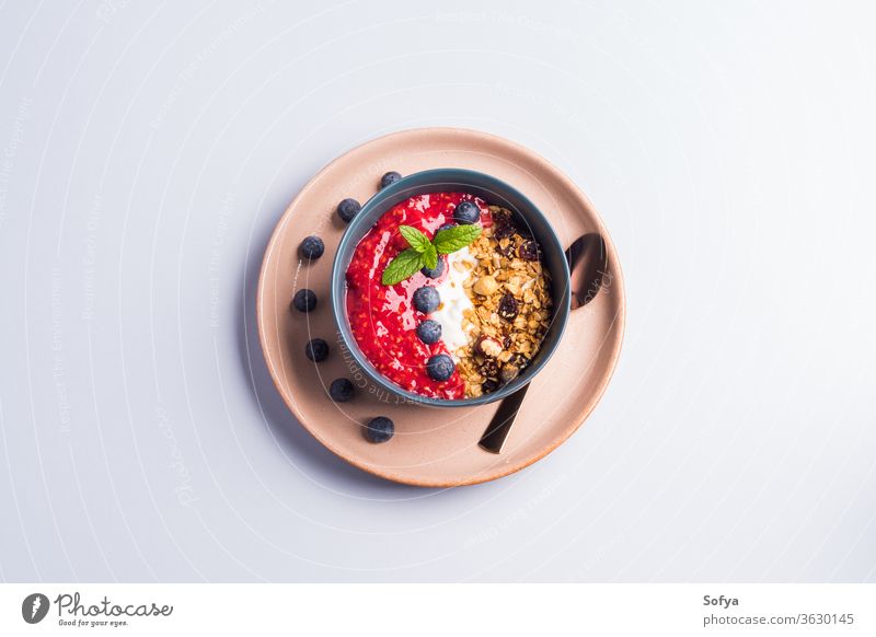 Yogurt bowl with raspberries and granola yogurt smoothie colorful blueberry pastel wooden background nuts breakfast dessert food vegan diet healthy organic