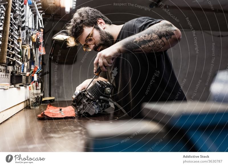 Focused male mechanic working in workshop repair master detail man vehicle workbench fix brutal side professional equipment tool garage occupation focus