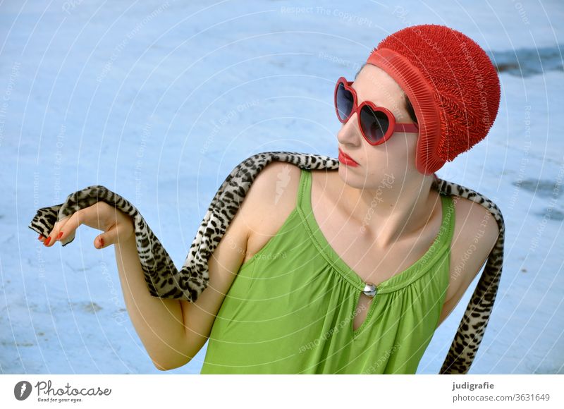 The girl with the beautiful red bathing cap and green swimsuit sits elegantly in the empty non-swimmer's pool. A summer love. Girl Woman Swimwear Bathing cap