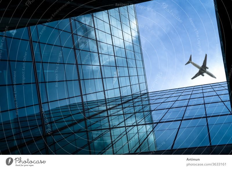 Airplane flying above modern glass office building. Perspective view of futuristic glass building. Exterior of office glass building. Business trip. Reflection in transparent glass. Company window.