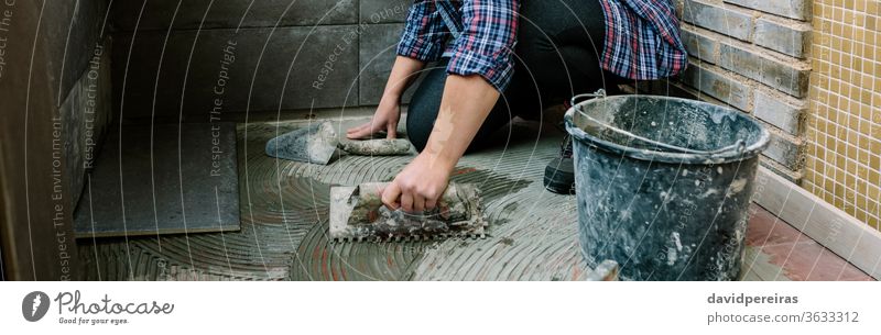 Female mason laying tiles on a terrace woman workman tiling floor imitation cement tile spread tiler glazed terrace working construction banner web panorama