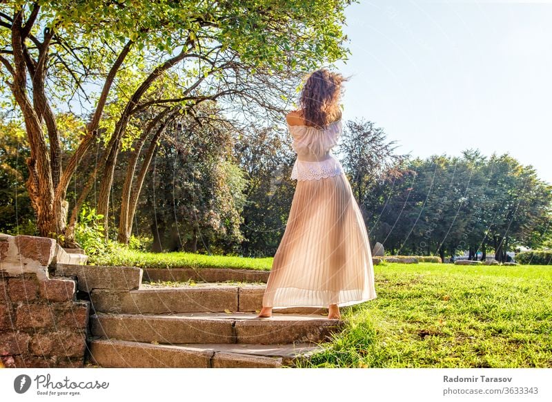 young girl in a light dress standing with her back in the park on sunny summer day woman one beauty nature lifestyle outdoor beautiful female person people