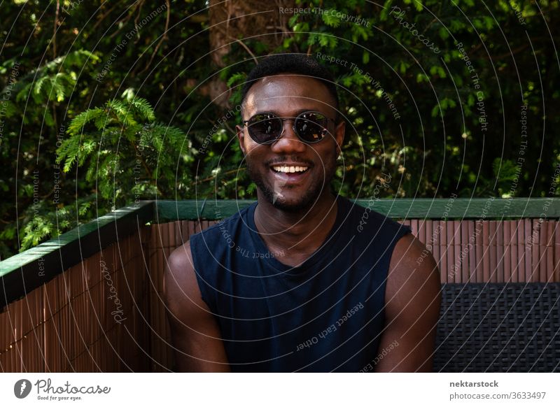 Young Black Man Smiling at Camera Outdoors 1 person African ethnicity man sunglasses lifestyle looking at camera terrace balcony summer tank top smile happiness