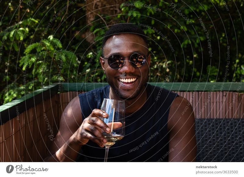 Handsome Black Man Holding Cup of Wine Smiling Widely Outdoors 1 person African ethnicity man sunglasses wine white wine cup holding lifestyle looking at camera