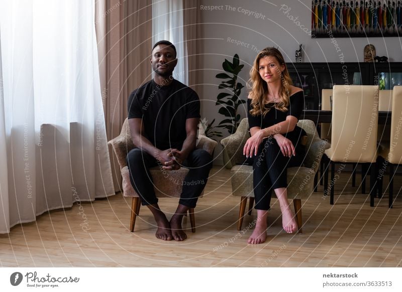 Portrait of Mixed Race Couple Seated in Living Room Armchairs lifestyle couple 2 people male female portrait mixed race couple real life real people full length
