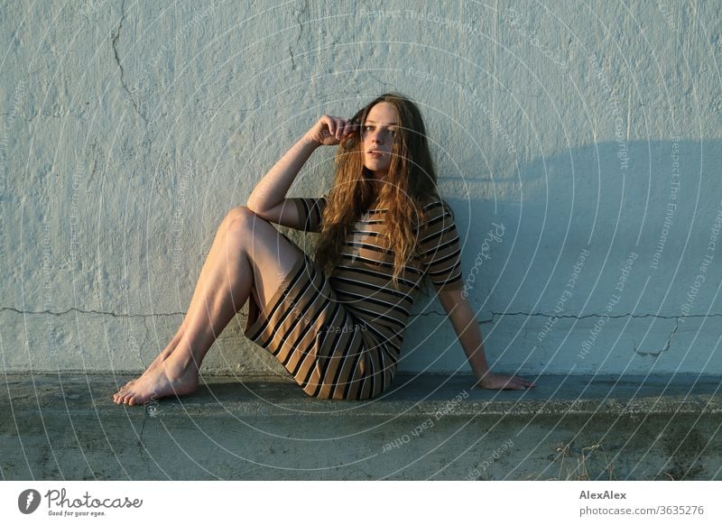 Portrait of a young woman sitting on a concrete wall at the beach Intensive girl Adults portrait Day Skin Sunlight Self-confident Central perspective