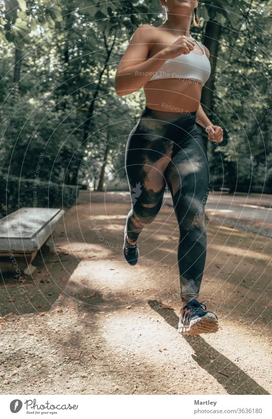 Body of a fit woman running through a park in summer. Fitness model outdoors in nature. Concept of getting fit, losing weight and healthy life sport fitness