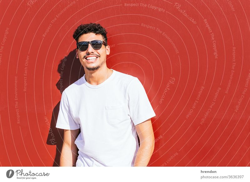 portrait of a young man with sunglasses smiling on a red wall male guy smile lifestyle happy attractive happiness posing beard positive leisure nature cool