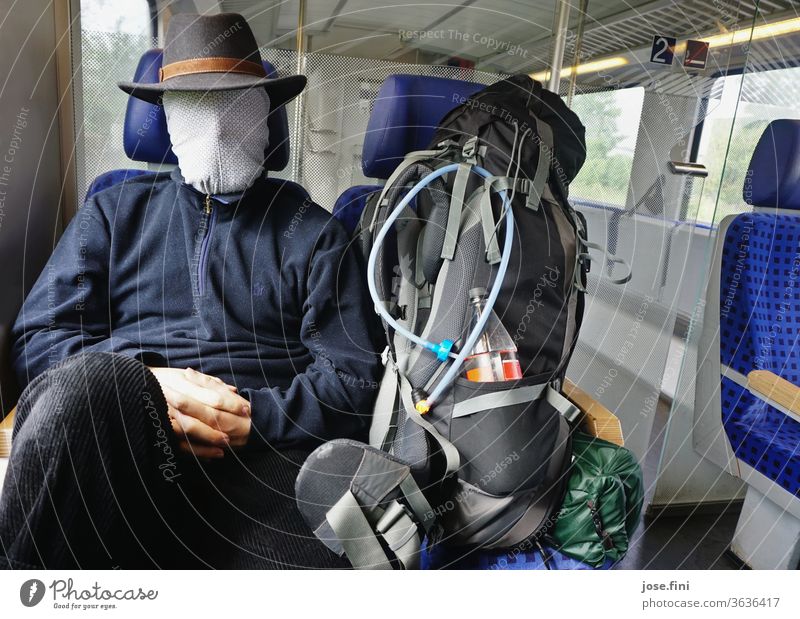 Train journey in corona times Young man go by train Track public transportation Sit Wait Backpack Backpacking Mask covering coronavirus Faceless Passenger