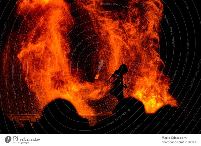 Silhouette of a firefighter fighting to contain a raging fire as a crowd looks on saving lives essential worker everyday hero firefighting disaster ablaze