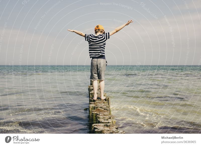 Boy balances on wooden bollards at the Baltic Sea Summer shirt T-shirt Stripe Joie de vivre (Vitality) Joy Coast vacation holidays Surf firecracker Waves Water