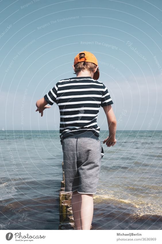 Boy balancing on bollards in the Baltic Sea Boy (child) Child Schoolboy one person children balance fun Ocean Water Waves firecracker Surf Coast vacation