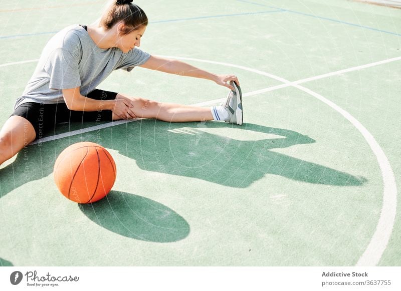 Female basketball player sitting on sports ground a Royalty Free
