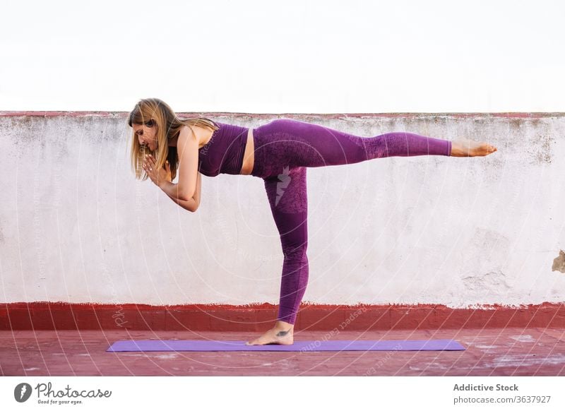 Calm woman practicing yoga in Warrior position warrior pose practice balance namaste gesture healthy mat terrace female harmony asana concentrate meditate