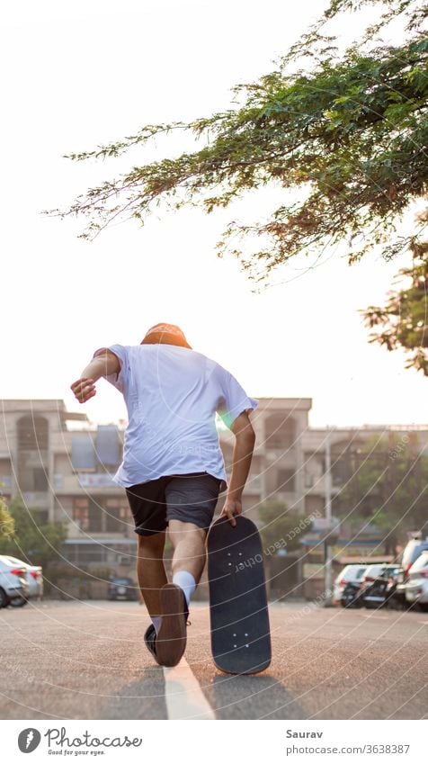 A Young adult charging forward with his skateboard on an empty road during sunrise. summer skateboarding recreation covid-19 empty street new normal outdoors