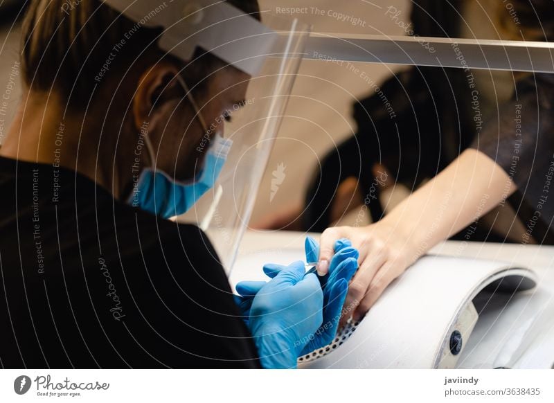 Aesthetician doing the manicure, filing the nails with a file to his client in a beauty center nailpolish fingernail woman salon manicurist care hand service