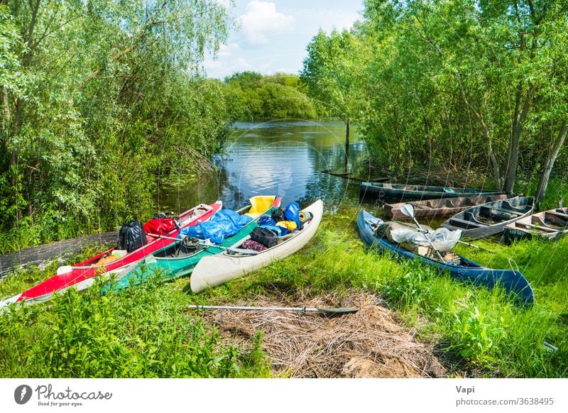 Many loaded kayaks with cargo on river boat water canoe trees activity summer vacation travel bags fishing boat bushes recreation kayaking leisure nature shore