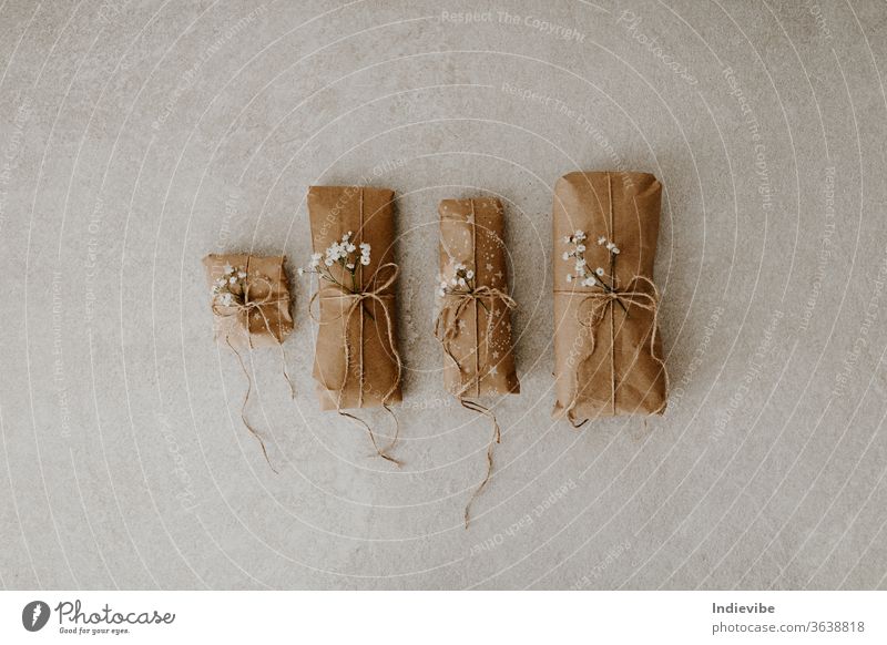 Four gift wrapped in paper with dried flower and string on marble background package wrapping holiday surprise reusable zero waste plastic free handmade minimal