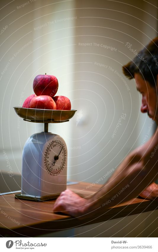 Man uses an old kitchen scale to determine the weight of a few apples Scale Weight read Reading figures kg Pound Display precise Accuracy fruit Preparation