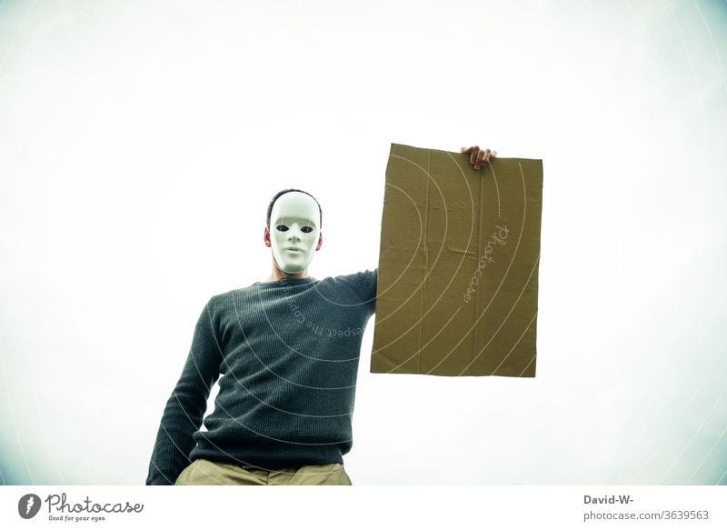 anonymous - masked man holds an empty cardboard sign in the air Cardboard Anonymous paperboard Mask anonymity cardboard box Man Clue indicative Safety point