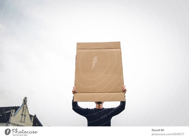 a man holds up a cardboard sign in the air and covers his face expression of opinion Freedom of expression observantly 1 Person Neutral background paperboard
