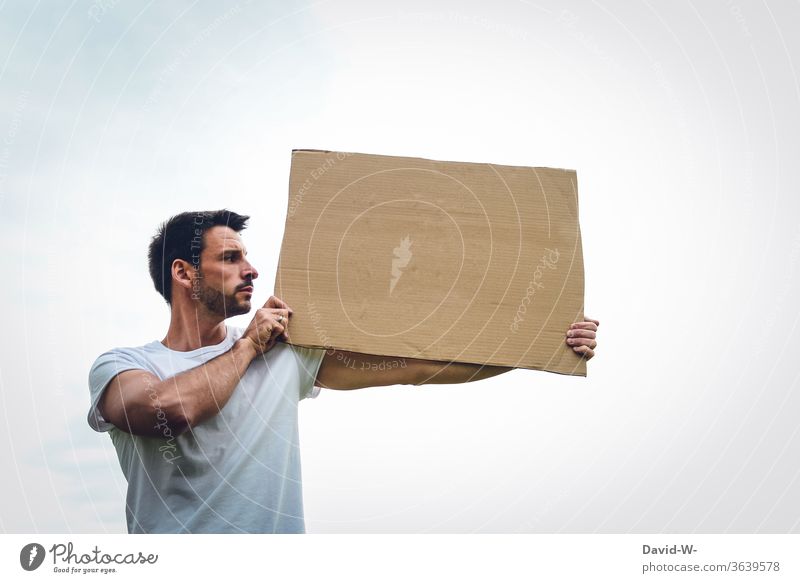 a person holds a cardboard sign in his hands, presents it and looks at what might be written there expression of opinion Freedom of expression observantly