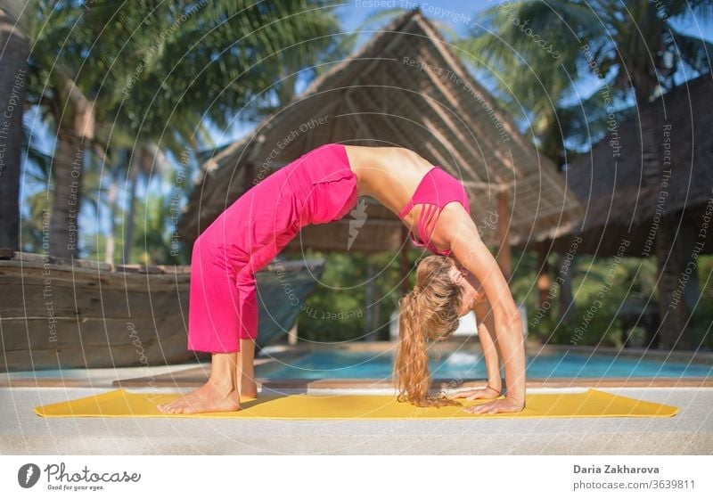 urdhva dhanurasana.photo of the girl doing yoga by the pool in a resort woman young pose lifestyle balance fitness female health exercise workout training