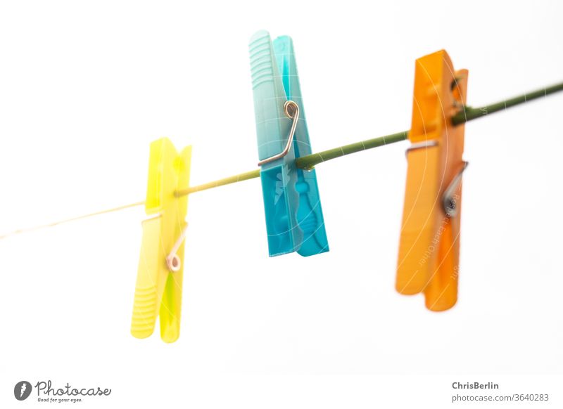 Three clothes pegs on a line against a white background Clothes peg three Clothesline Yellow Blue Orange White Neutral Background Light