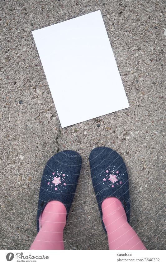 woman in slippers is standing in front of a blank sheet of white paper lying in the street, which can be written on. Woman Stand Slippers Asphalt Street Paper
