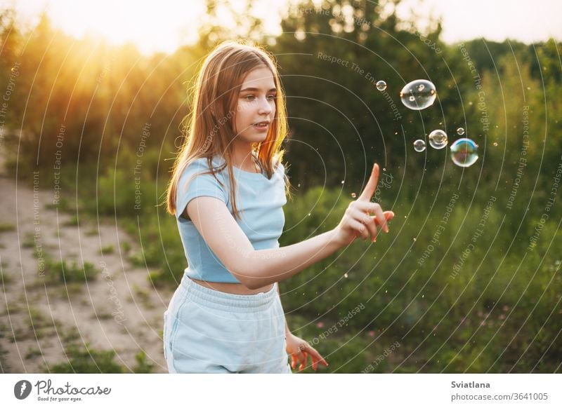 Cute girl with a beautiful smile catches soap bubbles on the background of a beautiful sunset. little blowing cute kid fun child childhood summer healthy pretty
