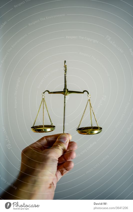 Hand holds a scale and compares both sides with each other Scale Time Money concept Balance Weight Fairness Honest Justice judiciary Lady Justice Detail