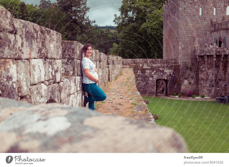 Pregnant woman on the ruins of a medieval castle pregnant looking at camera ramparts battlements tourism travel old abandoned architecture stone galicia